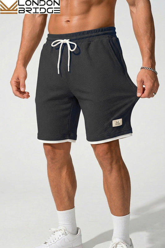 Person wearing black shorts with a visible brand logo on a white background